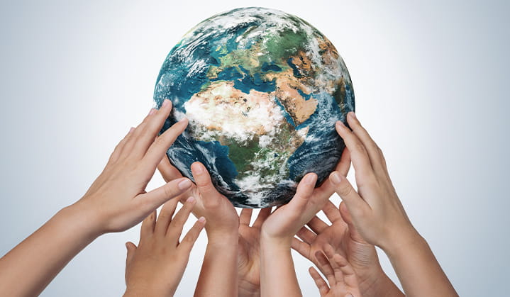 Manos alrededor del planeta Tierra mostrando valores comunes y unidad.